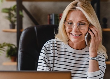 Woman with glasses smiling while talking on phone