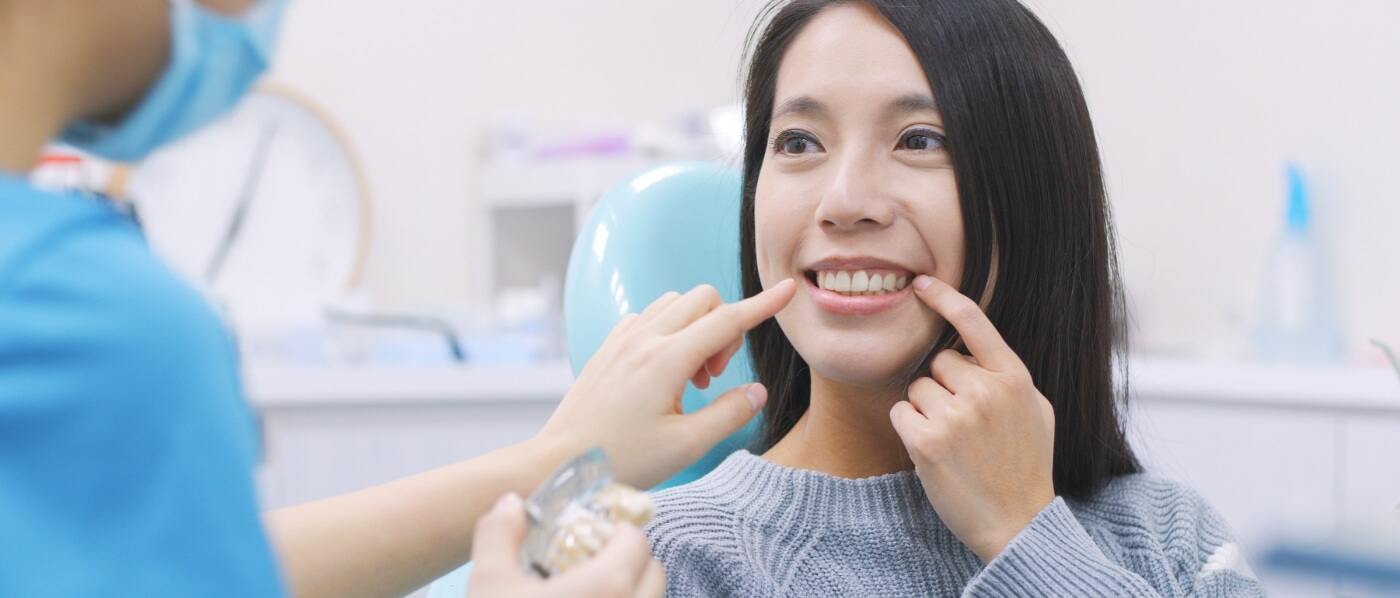 Dental patient pointing to her smile with dental implants in Downers Grove