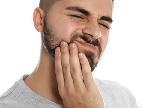 Man wincing and touching his jaw