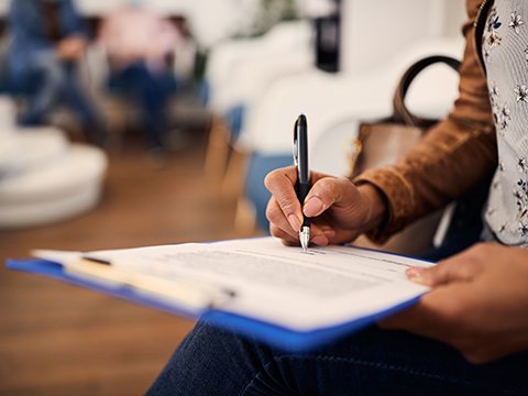Person filling out paperwork on a clipboard