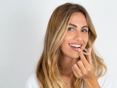 Smiling blonde woman holding Invisalign tray