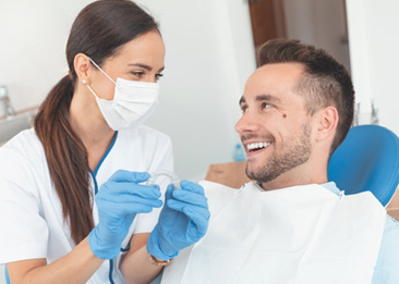Male patient smiling while listening to dentist talk about Invisalign 