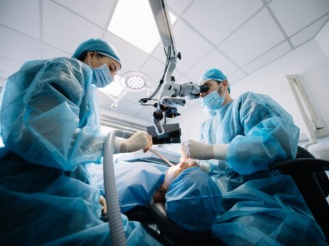 Two dentists performing dental surgery on a patient