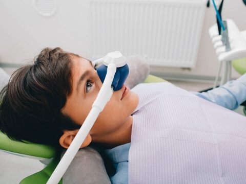 Young boy in dental chair wearing nitrous oxide mask