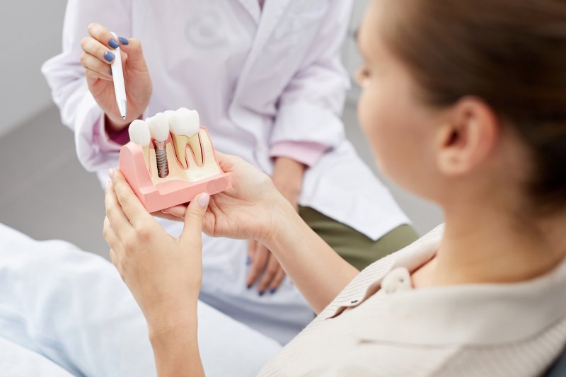 A patient holding an enlarged dental implant model